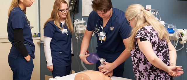 Healthcare professionals practicing emergency medical procedures on a patient simulator mannequin.